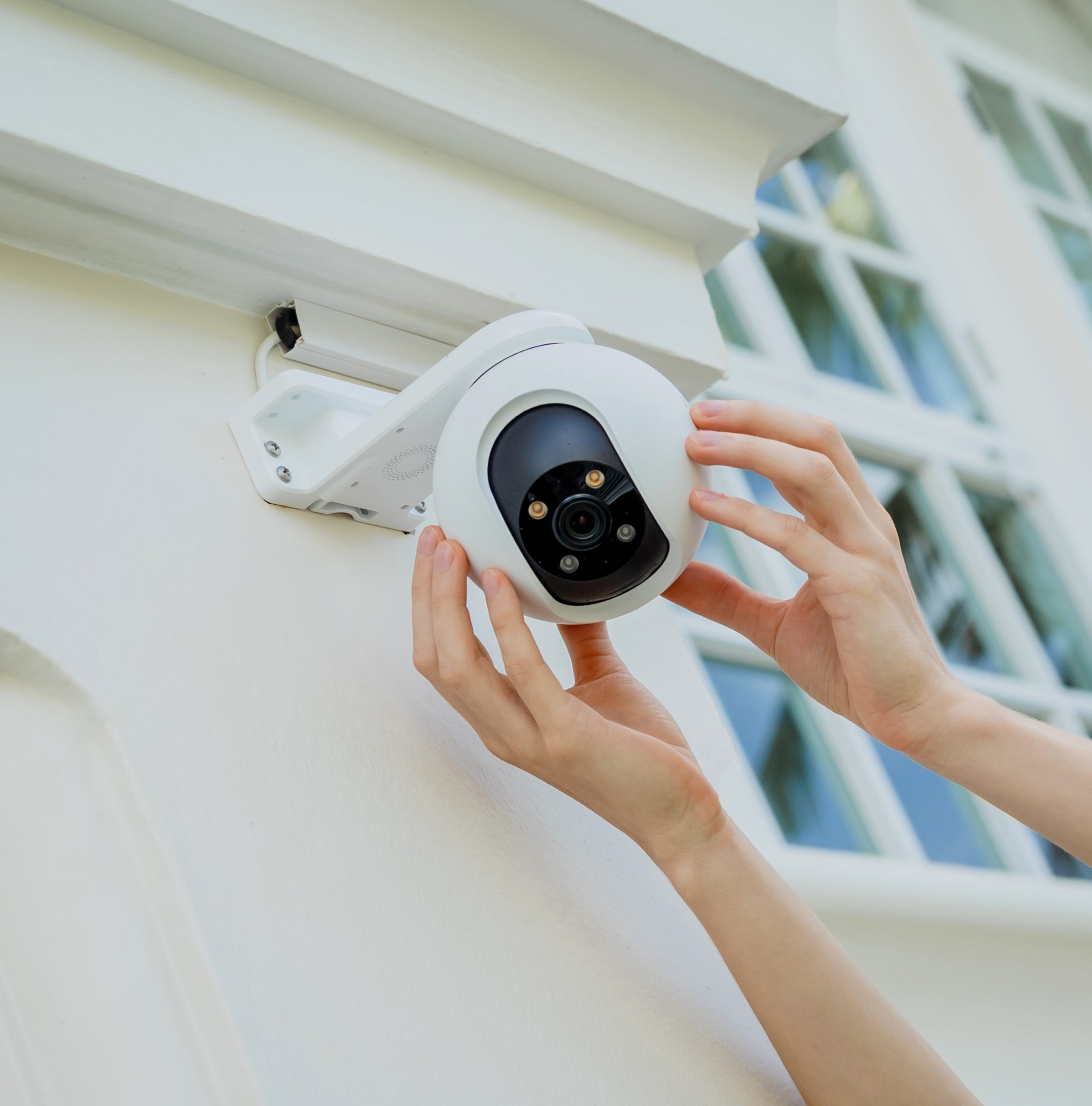 A technician installs a CCTV camera on the facade of a residential building
